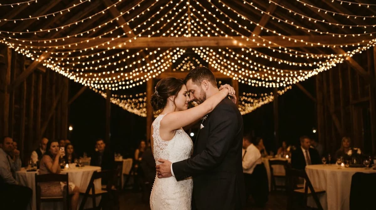 Bride and groom sharing their first dance under string lights at a barn wedding reception